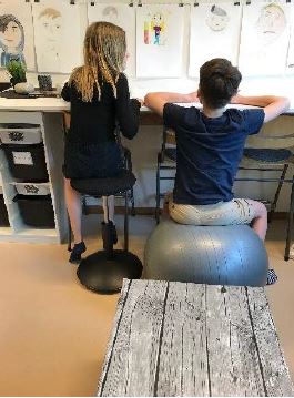Elever som sitter på pilatesboll och ergonomisk pall.